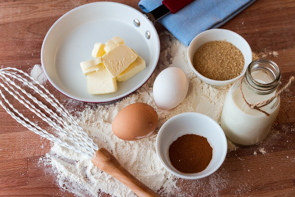 baking ingredients like flour, sugar, butter, and eggs arranged messily on a wooden table.